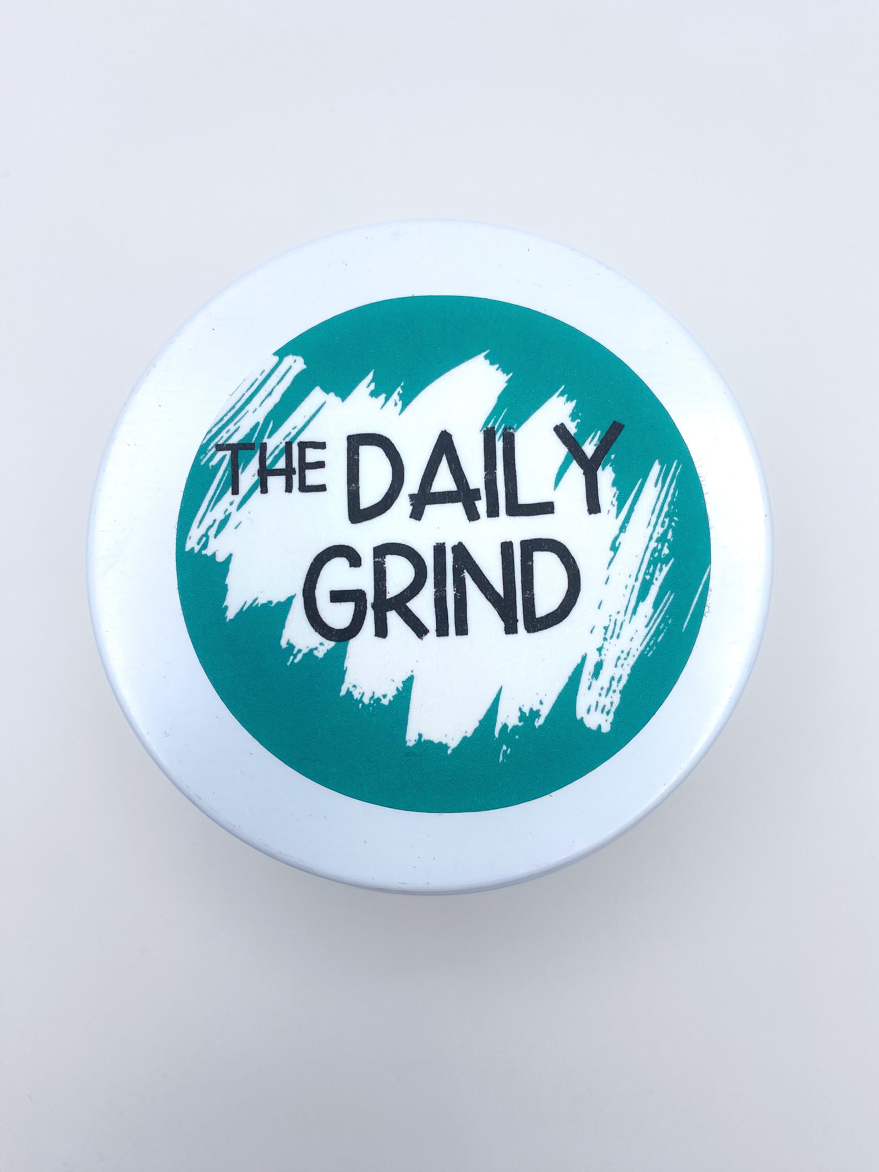 White candle lid with &quot;The Daily Grind&quot; label