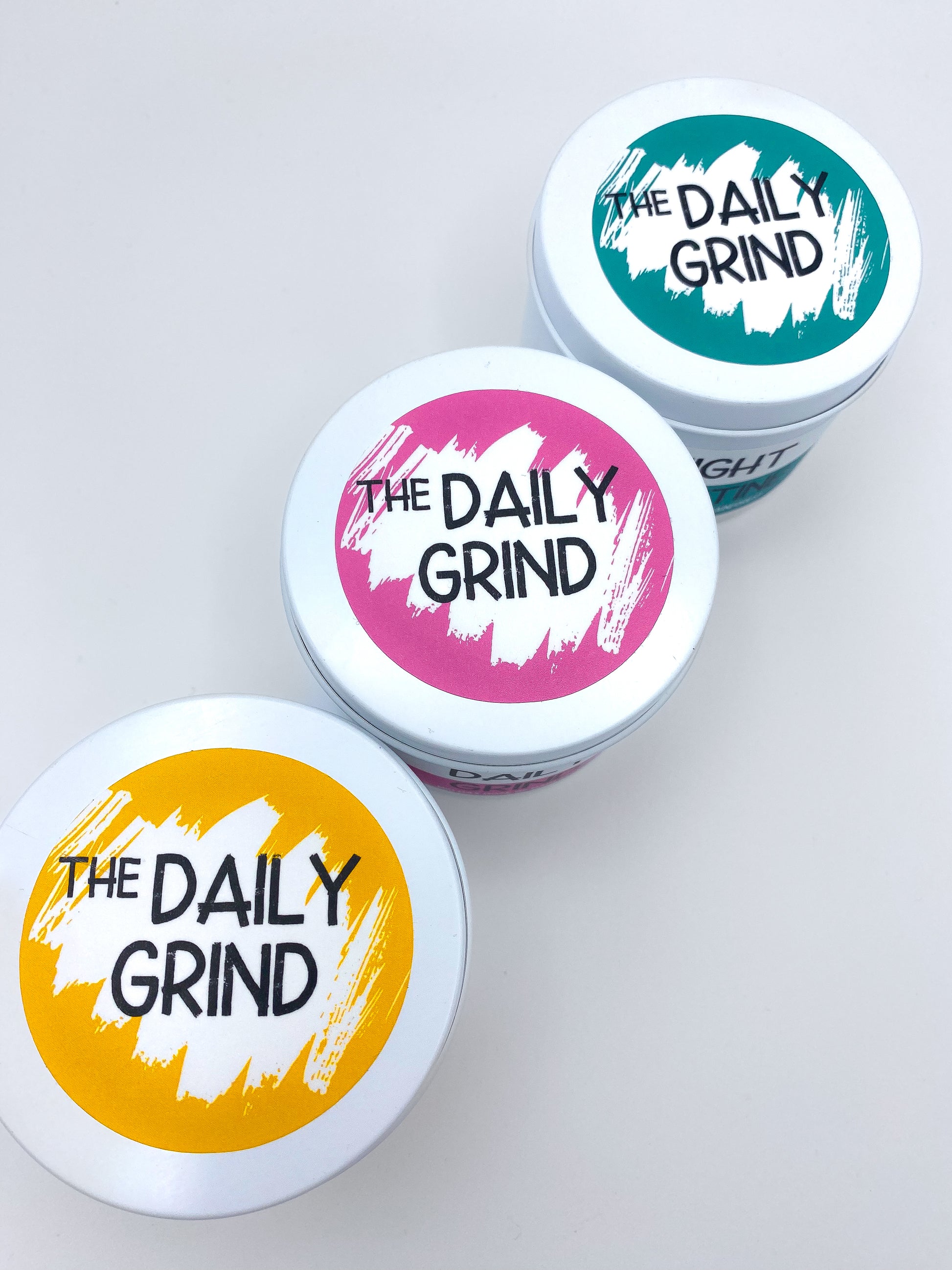 Lids of three candles with "The Daily Grind" labels