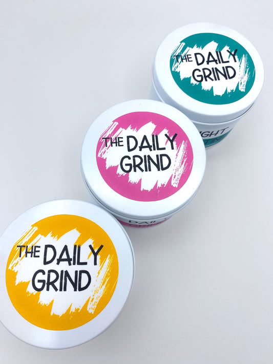 Lids of three candles with "The Daily Grind" labels