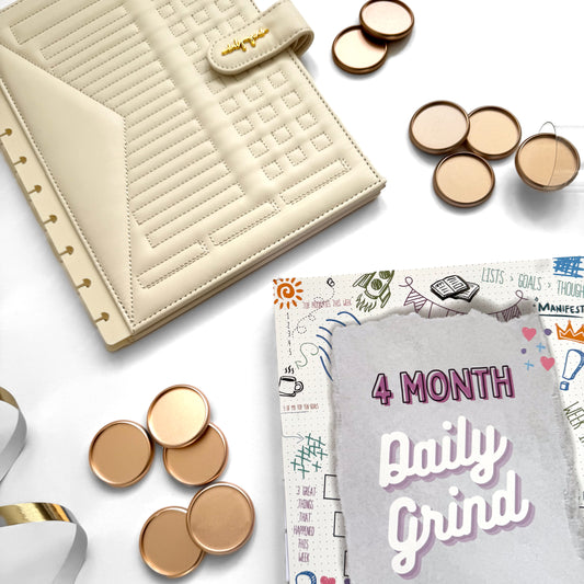 Cream planner cover and gold discs with "4 Month Daily Grind Sheets" insert