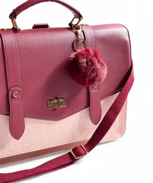 Pink handbag with a red pom-pom on a white background